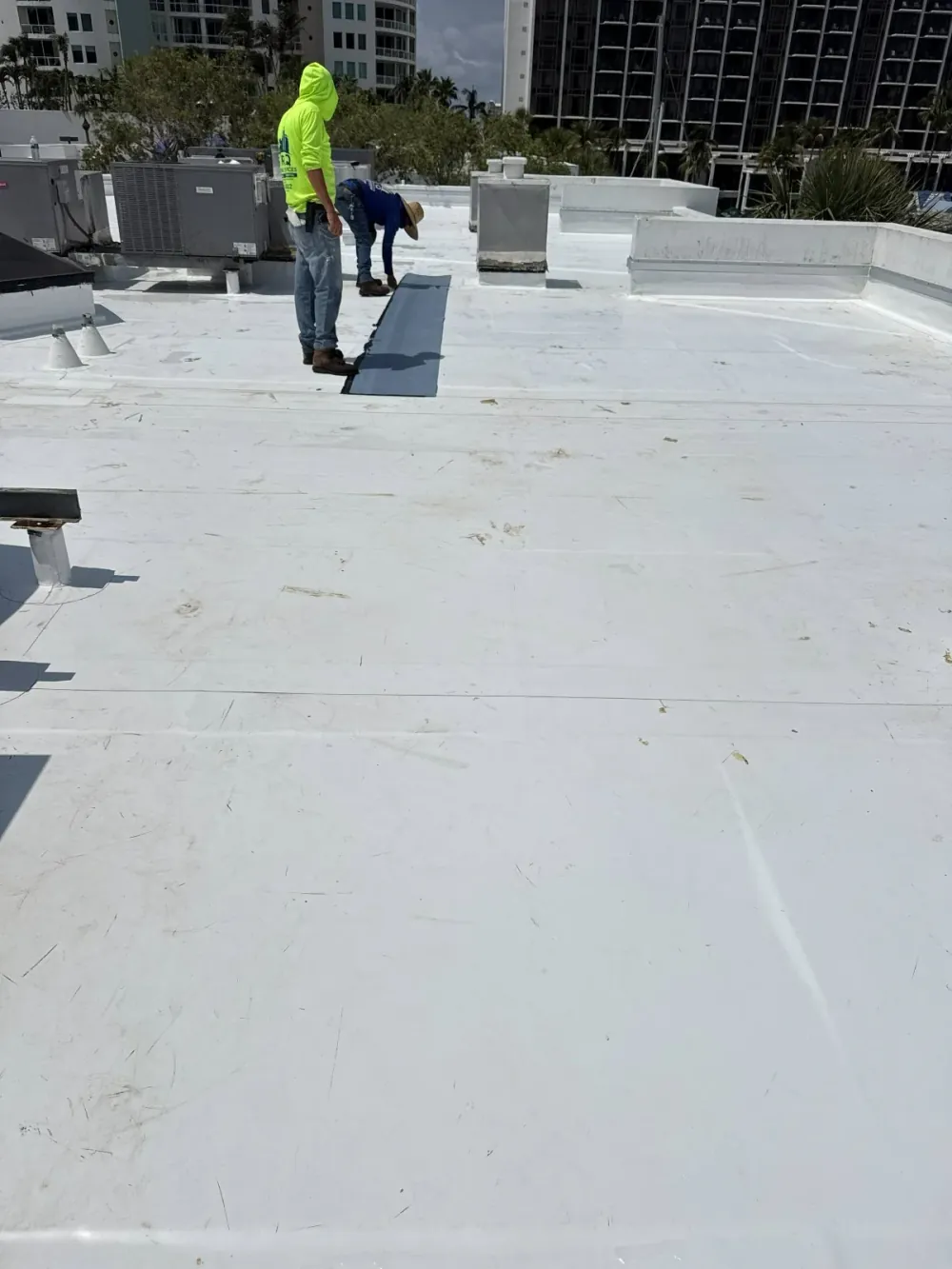 SRQ Building Services crew installing flat roof membrane in downtown Sarasota